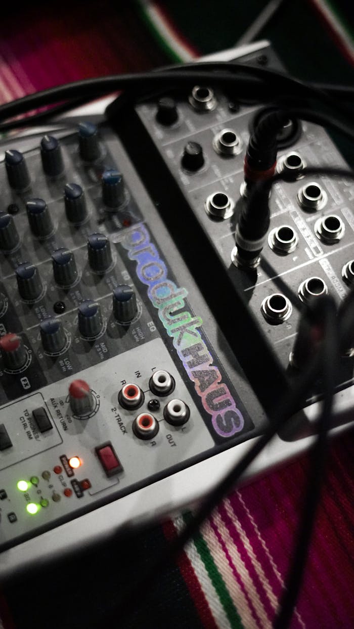 about-02 Close-up of an audio mixer with cables and controls for music production.